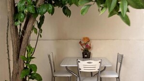 A small table with four chairs, a potted plant with flowers, and a tree trunk. - Carvan Hotel (Istanbul)