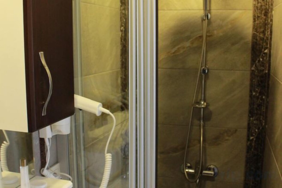 Badkamer | Een douche, een haardroger, pantoffels, handdoeken