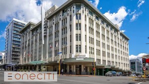 A large, multi-story hotel with a classic architectural design, featuring a prominent entrance and several flags. - Comfort Studio Getaway with Pool and Gym (Auckland)