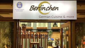 The exterior of a restaurant named 'Berlinchen' with a sign indicating it offers German cuisine and more. - Comfort Studio Getaway with Pool and Gym (Auckland)