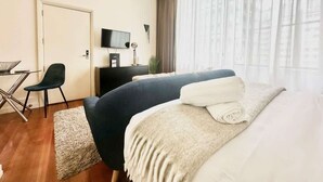 A hotel room with a bed, a desk, a chair, a TV, and a window with curtains. - Comfort Studio Getaway with Pool and Gym (Auckland)
