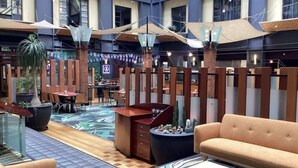 A spacious indoor area with a central seating area, tables, and potted plants. - Comfort Studio Getaway with Pool and Gym (Auckland)