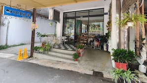 A building entrance with a checkered floor, potted plants, and a blue sign. - Sun and Moon Splendor (Yuchi)