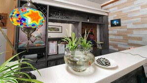 A reception area with a colorful mosaic lamp, a water feature with plants, and a decorative plate of seashells. - Sun and Moon Splendor (Yuchi)