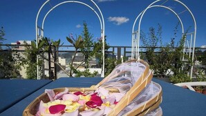 A sunbed with a basket of rose petals on a rooftop terrace with a clear sky. - Sun and Moon Splendor (Yuchi)