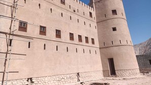 Un grande edificio a più piani con una torre imponente, caratterizzato da numerose finestre e una base in pietra.