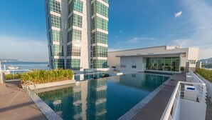 A rooftop pool with a view of the sea and a modern building.
