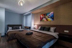 A modern hotel room with a large bed, a nightstand, a wall-mounted painting, and a ceiling light fixture. - Maritime Suites by The Only Bnb (George Town)