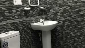 A bathroom with a toilet, sink, and tiled walls. - Sunrise Negombo by Celestial Ceylon (Negombo)