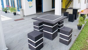 A modern outdoor area with a black and white striped table and benches, potted plants, and a staircase with yellow accents. - Sunrise Negombo by Celestial Ceylon (Negombo)