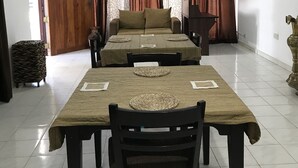 A dining area with a long table, two chairs, and a sofa. - Sunrise Negombo by Celestial Ceylon (Negombo)