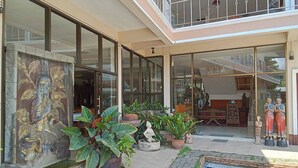 Un hall espacioso con puertas de cristal amplias, un balcón con barandilla y varias plantas en macetas.