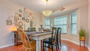 Un espace repas comprenant une table et des chaises en bois, un lustre et divers éléments décoratifs sur les murs.