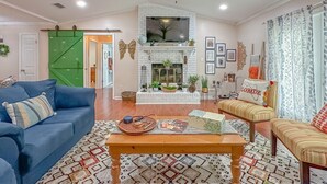 Un salon avec une cheminée, un ventilateur de plafond et un téléviseur.