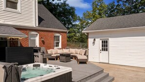 A backyard with a hot tub, outdoor furniture, and a garage. - ꕥLuxꕥHeated* Pool/Hot Tub/Gamerooms/Firepit/Outdoor Shower/Bunks (New Albany)