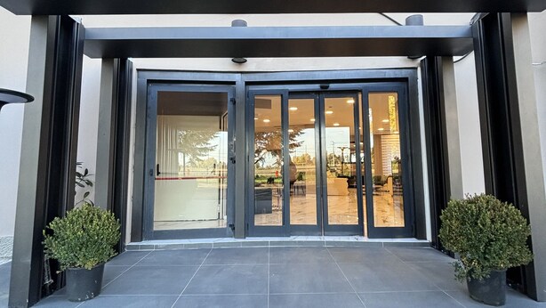Una entrada moderna de edificio con puerta de cristal y piso de baldosas.