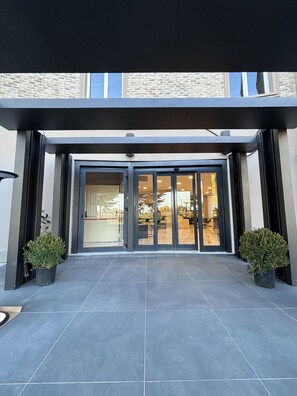 Una entrada moderna de edificio con puerta de cristal y piso de baldosas.