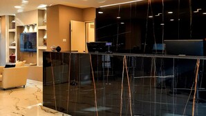 Un vestíbulo moderno con suelo de mármol, una recepción y un televisor en la pared.