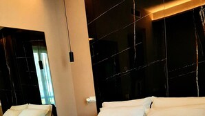 Una habitación de hotel con una cama, dos toallas enrolladas, una mesita de noche y un espejo.