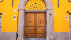 A double wooden door with a semi-circular arch above it, set in a yellow wall with a "no parking" sign. - RESIDENZA BELLA VITA (Modena)