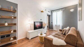 A modern living room with a flat-screen TV, wooden shelves, a brown sofa, and a round coffee table. - RESIDENZA BELLA VITA (Modena)