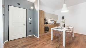 A modern kitchen with wooden cabinets, a dining table set for four, and a white pendant light. - RESIDENZA BELLA VITA (Modena)