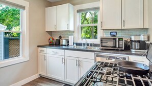 Uma cozinha moderna com armários brancos, fogão a gás, micro-ondas e máquina de café.