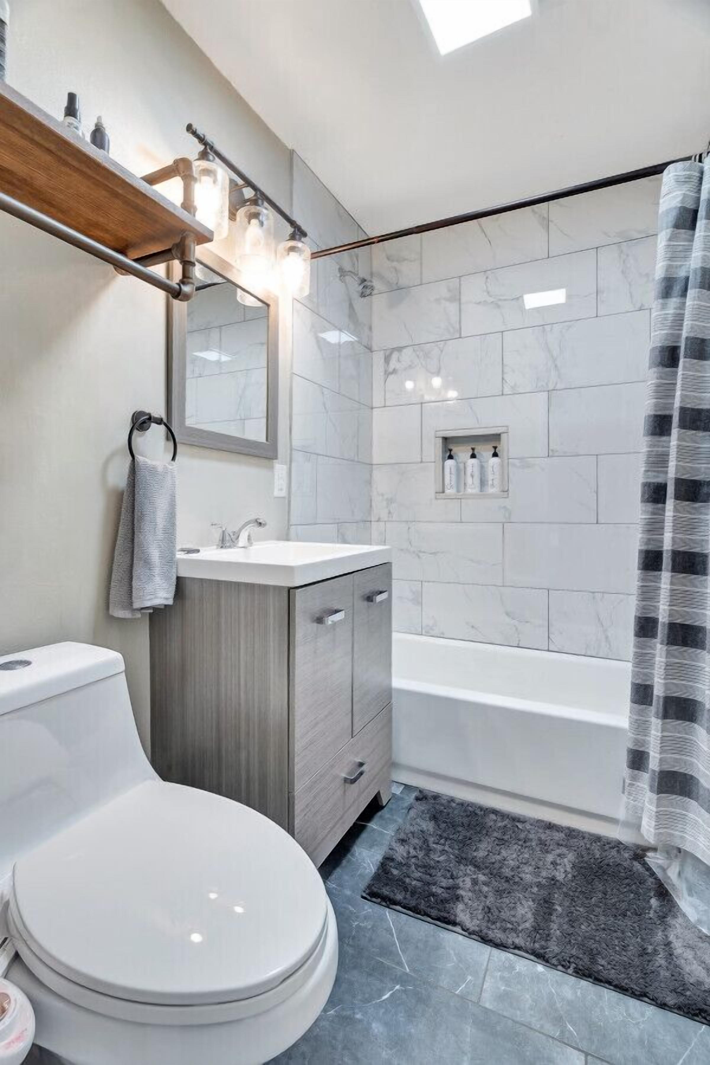 Ein modernes Badezimmer mit Toilette, Waschtisch und Badewanne.
