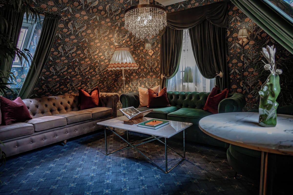 Ein Zimmer mit einer рарierten Couch, einem runden Couchtisch und einem grünen Sessel.