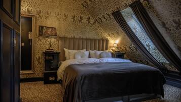 A bedroom with a large bed, a nightstand, a lamp, and a mirror.
