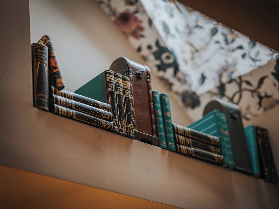 Una estantería con varios libros y un libro encuadernado en cuero.