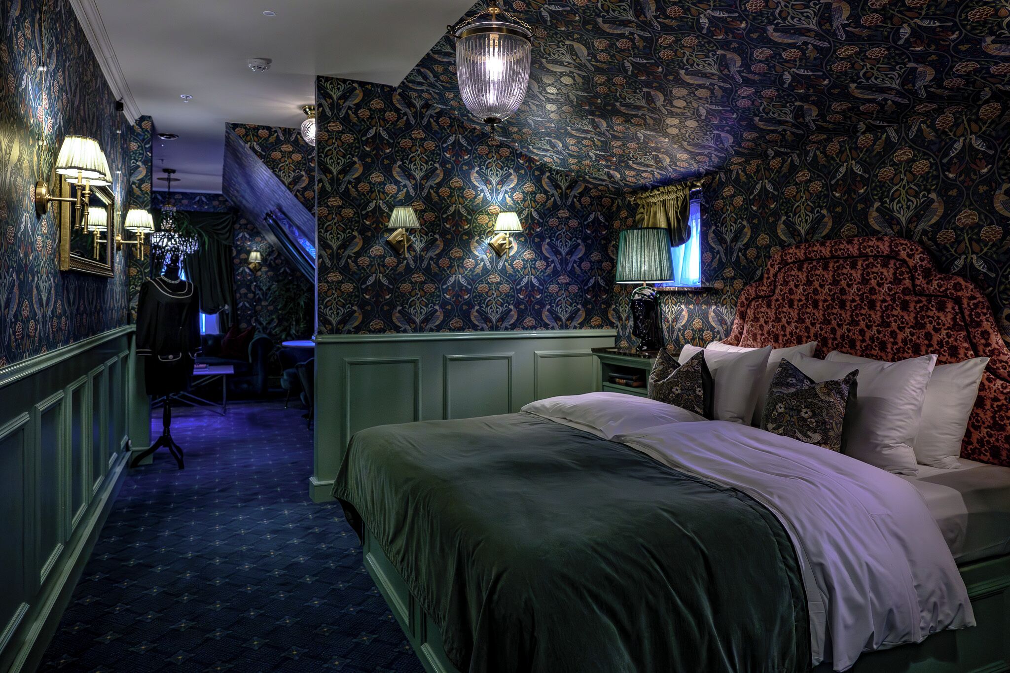 Un dormitorio con una cama grande, papel tapiz estampado y apliques de pared.