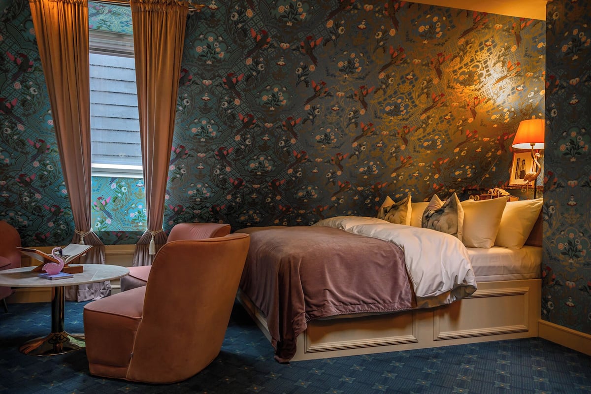 Ein Schlafzimmer mit Bett, Sessel, Tisch und Lampe.