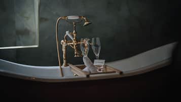 A bathroom vanity with a gold faucet, two wine glasses, and a tray with a name tag.