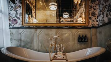 A bathroom with a freestanding bathtub, a large mirror, and a chandelier.