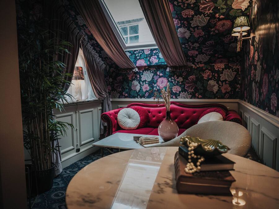 Een knus ingerichte kamer met een rode bank, een tafeltje en een plant in pot.