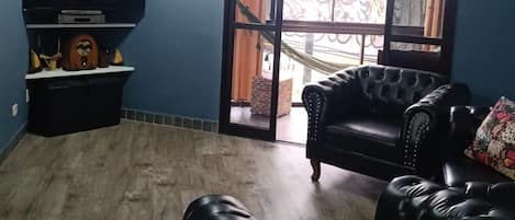 Una sala de estar con un televisor de pantalla plana, un sofá y un ventanal corredizo que da a un espacio exterior.