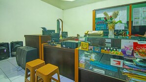 Un espace d’accueil comprenant un comptoir, un ordinateur et deux tabourets en osier.