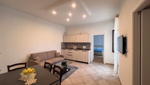 A compact living space with a dining area, kitchenette, and a bedroom. - B&B Aurora (San Marcello Piteglio)