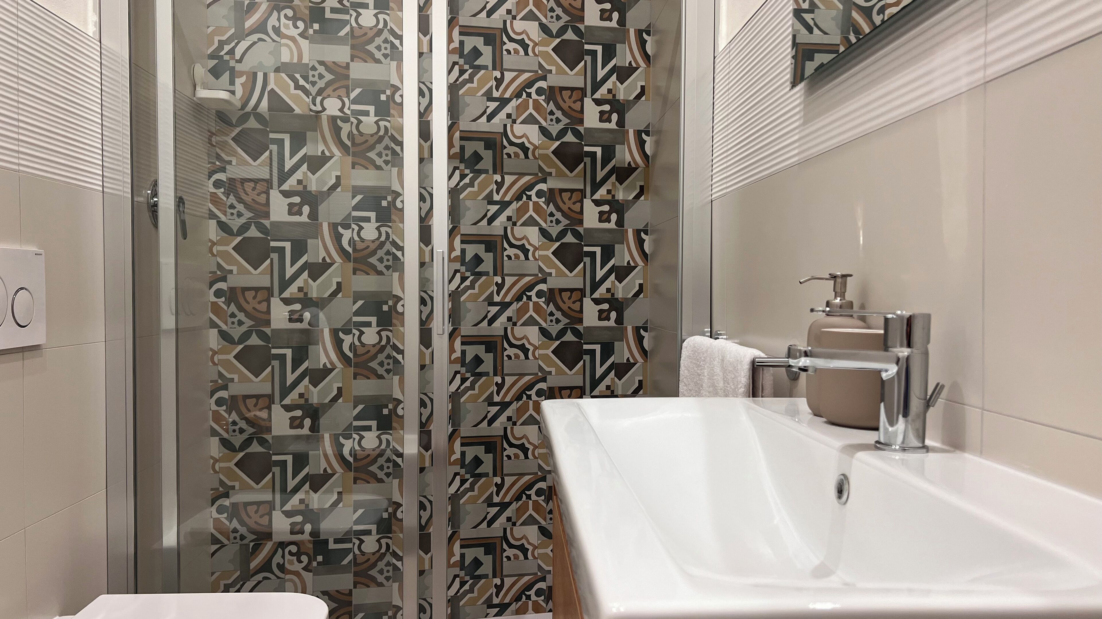 Un baño moderno con cortina de ducha estampada, un lavamanos blanco y un perchero para toallas.