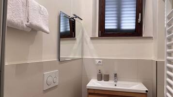 Un baño pequeño con inodoro, lavamanos y espejo.