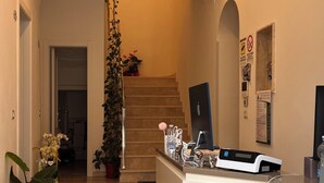 A modern reception area with a desk, a staircase, and potted plants. - B&B Aurora (San Marcello Piteglio)