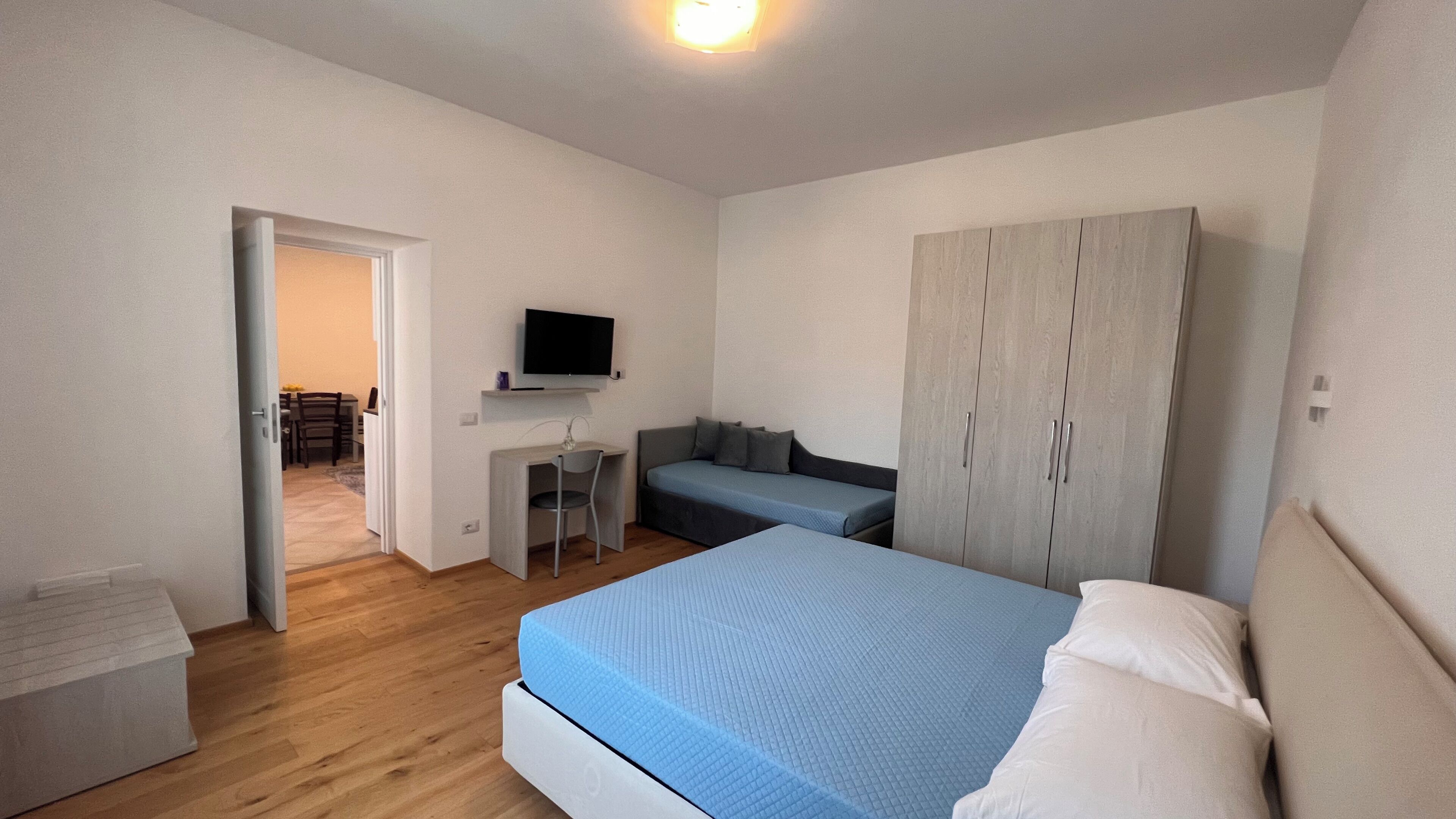 Ein Schlafzimmer mit einem Bett, einem Schreibtisch, einem Fernseher und einem Kleiderschrank.