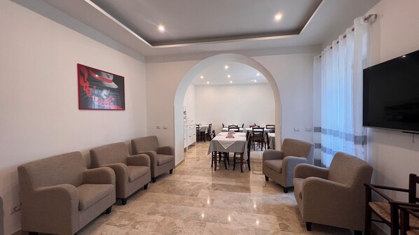 A spacious living area with a dining table, sofas, and a TV.
