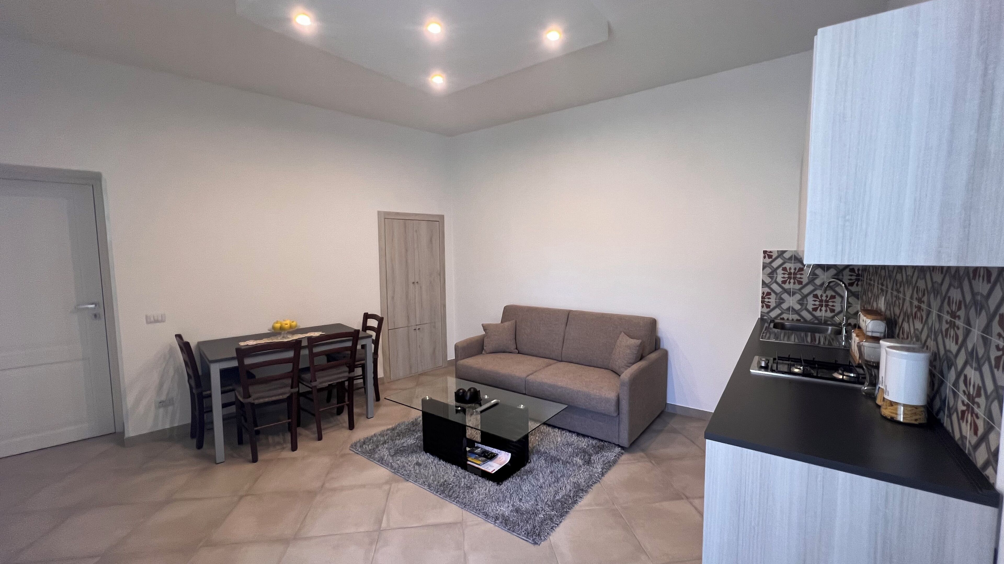 A compact living space with a dining area, a sofa, a coffee table, and a kitchenette.