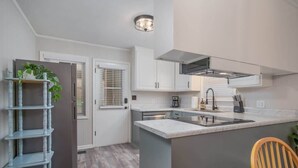 A modern kitchen with white cabinets, a central island with a sink, and a built-in stove.