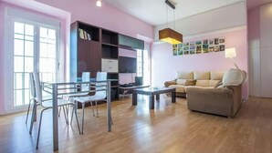 Una sala de estar moderna con una mesa de comedor de vidrio, un sofá color beige y una estantería.