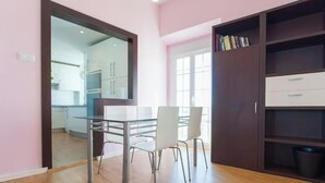 Una cocina moderna con armarios blancos y un ventanal que da a un comedor con mesa y sillas de vidrio.