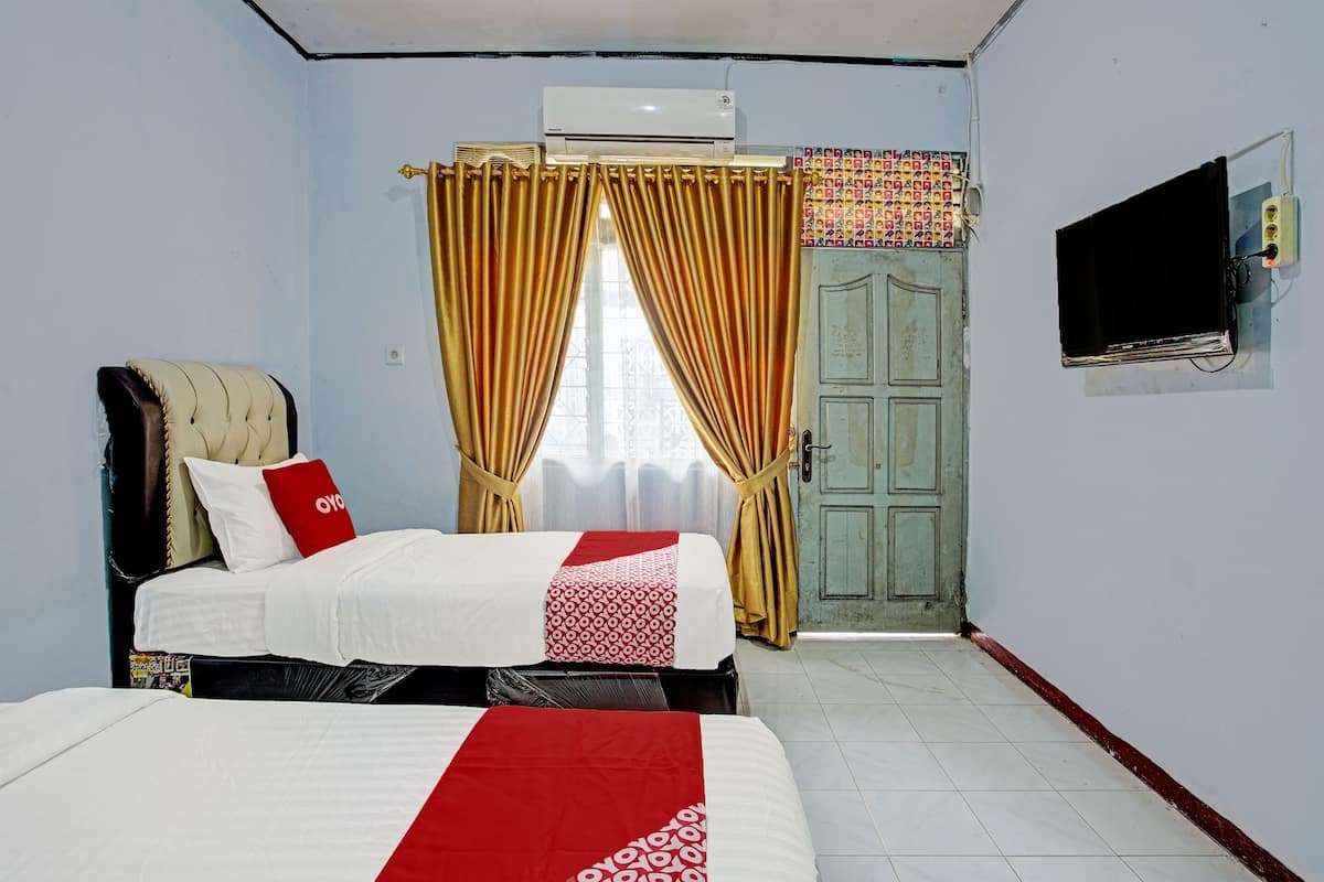 Une chambre d’hôtel avec deux lits, une télévision et une porte ornée d’un rideau coloré.