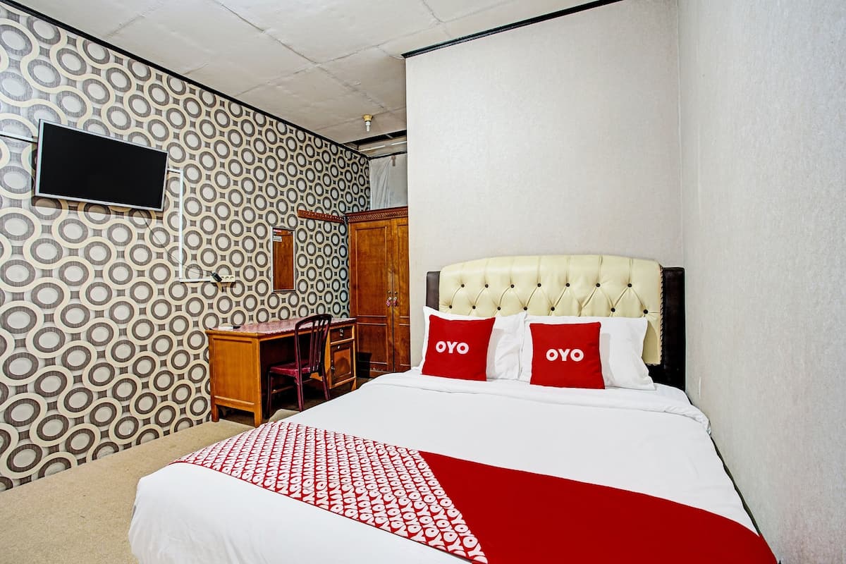 Une chambre d’hôtel avec un lit, un bureau et une télévision.